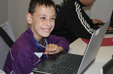 Young adult smiling and working on his laptop