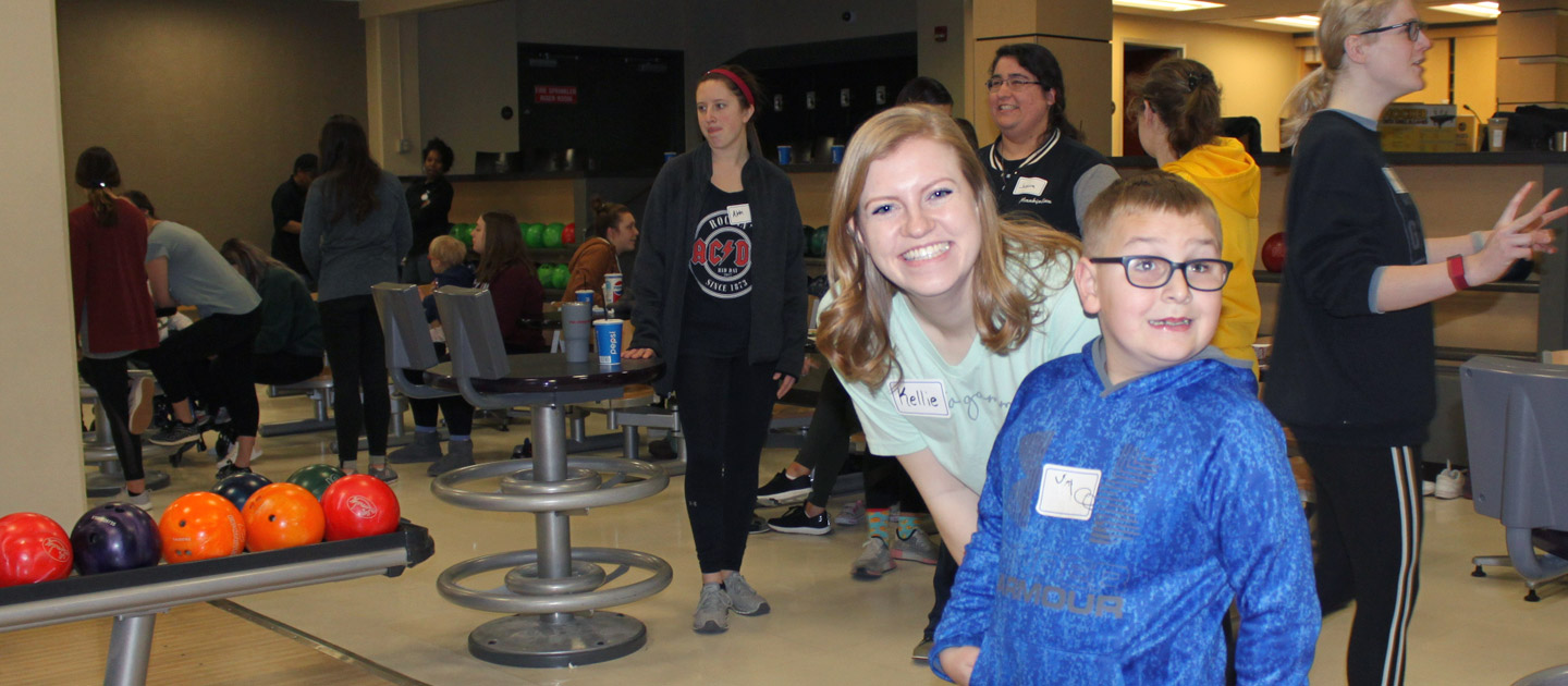 Boy who is visually impaired enjoys his time bowling with a DG mentor while his parents are at the Family Support Group.
