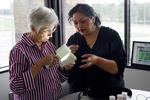 A client of services being shown how to use a magnifying glass with a flashlight.