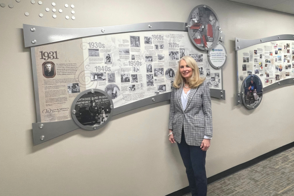 Suzanne standing in front of the Envision Dallas history wall