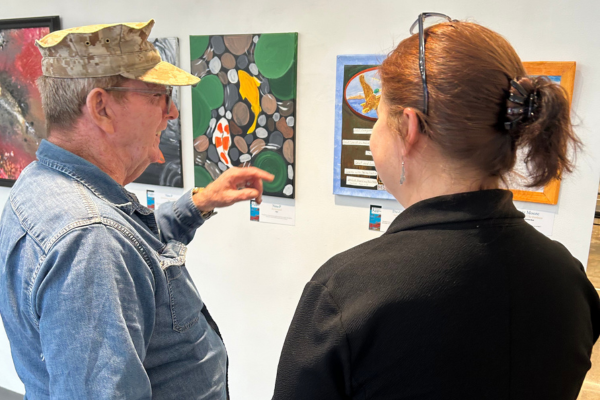 A veteran smiling as he looks at artwork