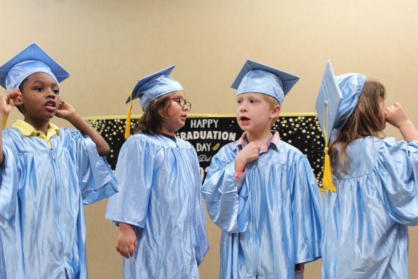 Pre-k graduates in their caps and gowns standing in line waiting to be called by name.