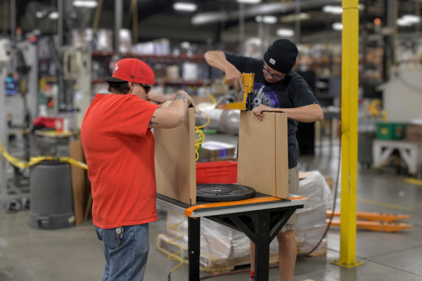 Two employees putting replacement parts in a box.