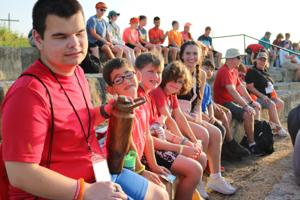 The boys group at camp smiling around the campfire.