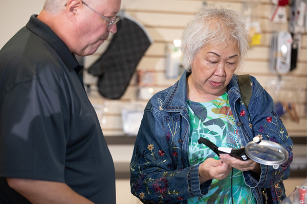 Lady trying a magnifier at the Envision Everyday Store.