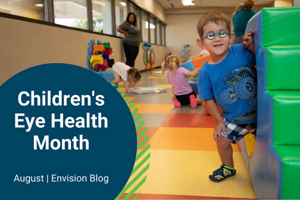 Little boy with glasses coming out from behind a toy block tower, Children's Eye Health Month