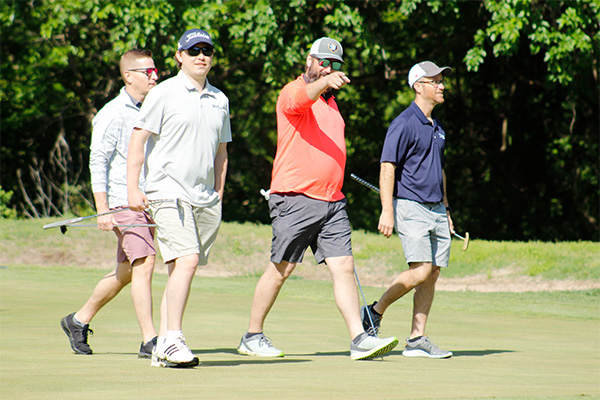 Golf team walking off the green celebrating their shots.